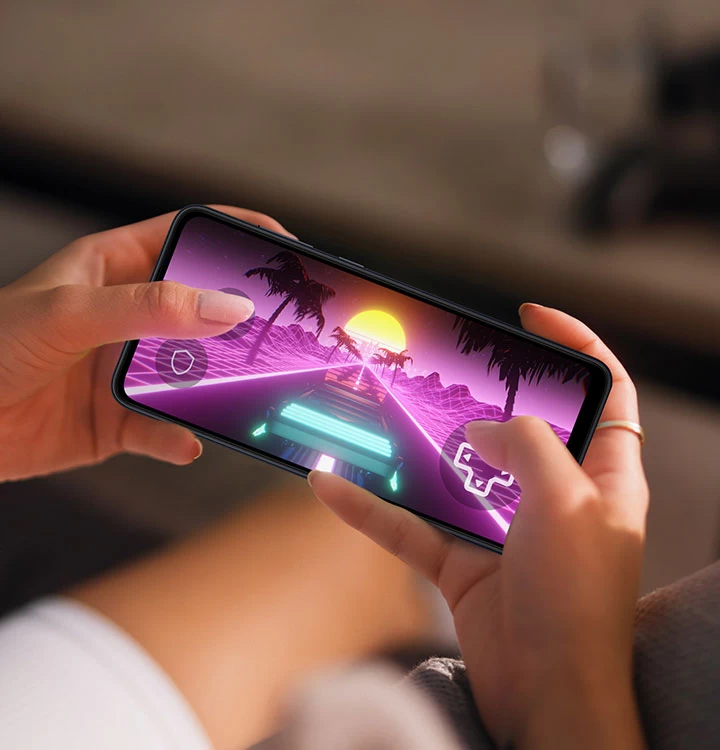 'Duas mãos segurando um Galaxy A05 mostram uma gameplay de corrida na tela.